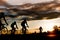 Group of men ride bicycles at sunset with sunbeam over