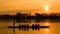 Group of men rowing over the river at sunset