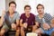 Group Of Men Sitting On Sofa Watching Sport Together