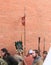 Group of men in suits of ancient soldiers near a red brick wall