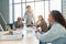 Group of men and women having casual discussion during meeting sitting in office