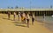 A group of men and women with large bellies gaze out to sea from the beach at the Old Town in Albuferia in Portugal