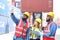 Group of men and women of professional container operators standing in shipping container yard look at the camera and show thumbs