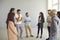 Group of men and women standing in office and having discussion with business trainer