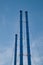 Group of metal chimneys of small local power station or heating boiler against blue sky.