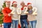 Group of middle age friends smiling happy celebrating new year standing by christmas tree at home