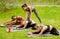 Group of millennial sporty girls practicing yoga with instructor at park