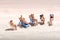 Group of miniature people sunbathing in deckchairs