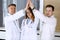 Group of modern doctors standing as a team while joining hands or giving five to each other. Physicians ready to examine