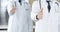 Group of modern doctors standing as a team with thumbs up or Ok sign in hospital office, close-up. Medical help