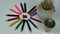 A group of multi-colored wooden pencils in the form of a sun and a pencil sharpener in the center, two cacti in clay