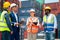 Group of multi ethnic cargo contianer workers stand and discuss together about the project  with happiness and stack of tank as