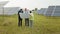 Group of multi ethnic people and safety helmets staring at solar farm and looking on drawings. Two engineers and