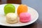 A group of multicoloured macaroon,a famous French dessert in a white plant on wooden dinning table