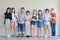 Group of multiethnic school kids hands together in line in classroom with happy smiling face on white wall background education