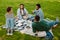 Group of multinational students friends studying together while sitting in park