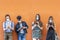 Group of multiracial friends with face masks in front of orange wall