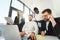 Group of multiracial office workers looking at laptop during meeting in boss`s office.