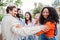 Group of multiracial young adult people bonding and embracing closeness on circle together. On foreground an african