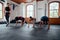 Group of multiracial young adults with trainer doing mountain climbers exercise at the gym