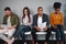 Group of multiracial young candidates waiting for interview sitting on chair holding their resumes