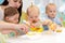 Group of nursery babies eating healthy food lunch break with kindergartener help