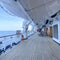 A group of passengers lounging in chairs under the life rafts on the deck of a cruise ship