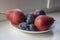 Group of pears and blue plums edible fruits, tasty ripened red yellow fruit on the table