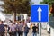 Group of pedestrians walking down the one way street with large traffic sign