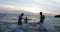 Group Of People On Beach At Sunset Running In Sea Making Splashes Cheerful Friends On Vacation