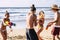 Group of people caucasian young friends have fun at the beach in summer holiday vacation playing with water guns and laughing a