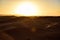 A group of people climbing a large dune at dusk of the Sahara.