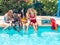 Group of people of different ethnic groups with bathing suits of different colors with the mobile in the hand sitting on the edge