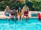 Group of people of different ethnic groups with bathing suits of different colors with the mobile in the hand sitting on the edge