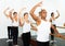 Group of people doing ballet exercises using barre in gym