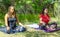 Group of people doing yoga exercise in the park, womans relaxing in the park