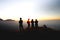 Group of people enjoying beautiful cloudscape sunrise on top of mountain cliff.