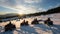 Group of people on four-wheelers ATV bikes, enjoying beautiful sunset in the the mountains in winter