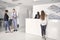 Group of people, four young businesspeople, meeting in modern office hallway, looking at papers