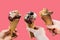 A group of people or friends holding ice cream in their hands on a pink background. Creative idea of a holiday or a