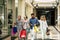 Group of people going shopping together at the mall holding shopping bags - two seniors and couple of adults looking stores