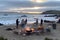 a group of people grilling on the beach, surrounded by the sound of waves and seagulls