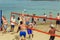 A group of people playing volleyball on the beach. A clear, sunny summer day. People rest on vacation