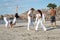 Group of people practice Capoeira on beach.