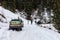 A group of people push out a car stuck on a snow-covered forest road