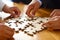 Group of people putting together jigsaw on wooden table. Generative AI