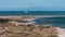 Group of people on the sandy beach of Skagen town on a sunny day with a ship sailing on the horizon