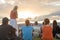 Group of people sitting on grass and enjoy sunset