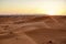 A group of people sitting on a large dune watching the sunset of the Sahara.