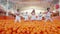 Group of people standing amidst a sea of oranges in a bright indoor setting, displaying a sense of abundance and freshness